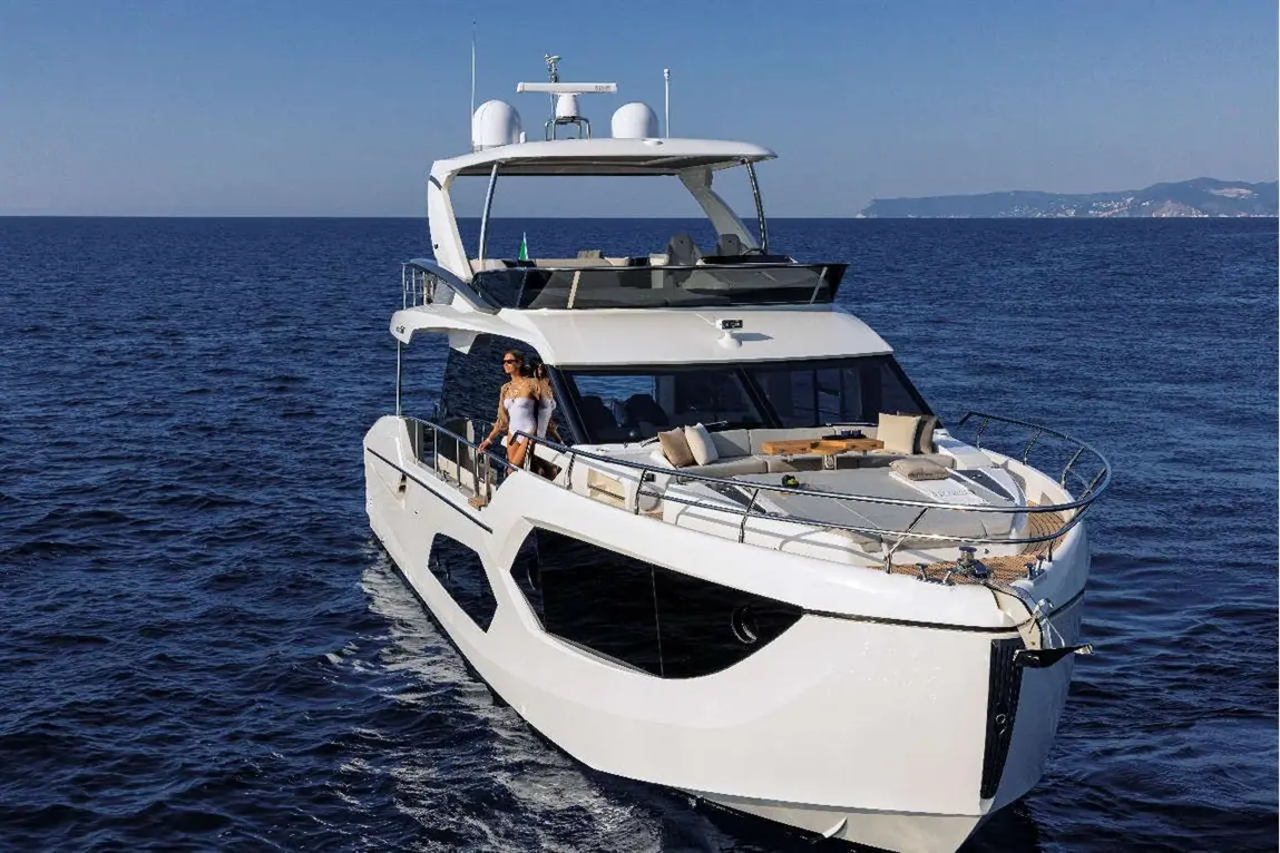Luxury yacht sailing on deep blue waters, featuring a woman in a white swimsuit relaxing on the deck with sun loungers.